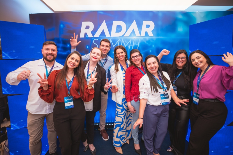 Grupo posa para foto diante de painel com marca do Radar Summit