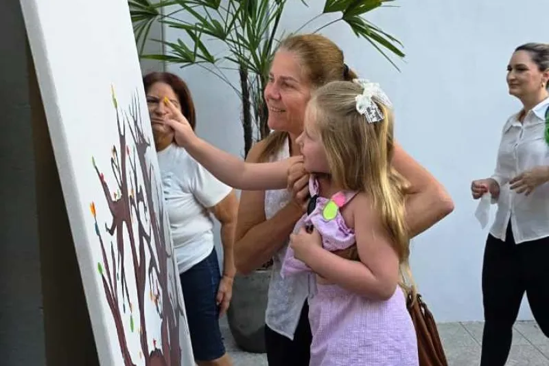 Ao lado da mãe, menina participa de atividade artística